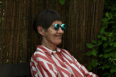 Smiling senior woman wearing sunglasses sitting in backyard