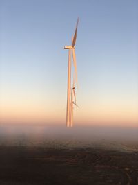 Low angle view of wind turbines in the morning fog. 