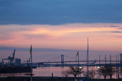 Suspension bridge over bay against cloudy sky during sunset