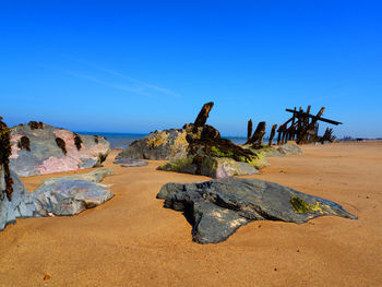 Scenic view of beach against clear blue sky