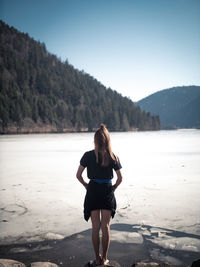 Rear view of woman on shore against sky