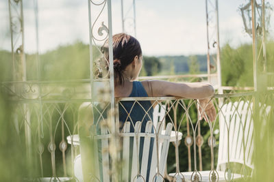 Rear view of woman sitting on chair in back yard