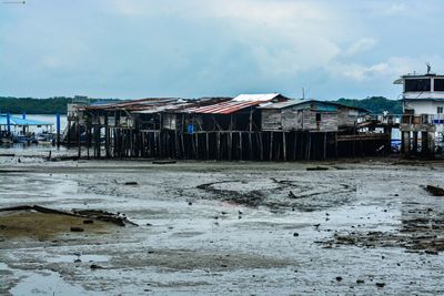 Houses on beach by buildings against sky