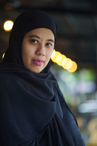 Portrait of indonesian muslim woman wearing black hijab with bokeh.