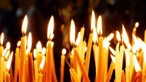 Close-up of lit candles in temple at night