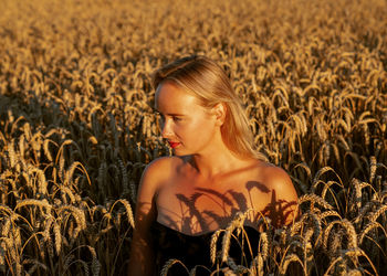 Young woman standing amidst wheat field