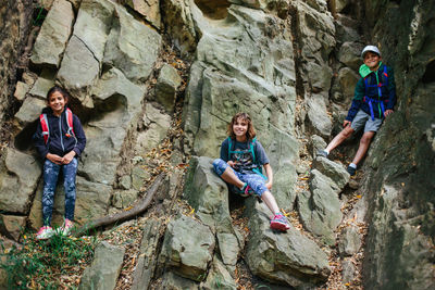 Low angle portrait of happy siblings climbing on rocks