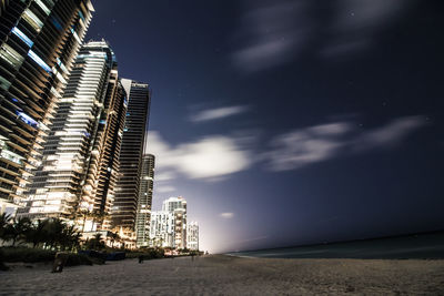 Low angle view of skyscrapers against sky at night