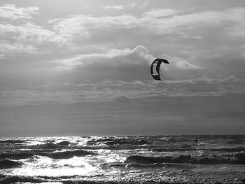 Man paragliding over sea against sky