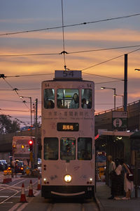 Cars on illuminated street against sky at sunset