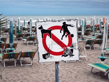 Chairs and tables on beach against sky