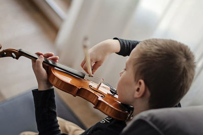 High angle view of boy playing violin at home