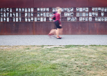 Two persons passing in front of wall memorial for victims of berlin wall