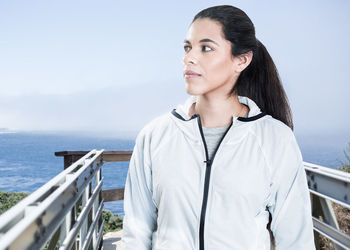 Young woman standing by sea on pier