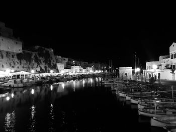 Boats moored at harbor against clear sky at night