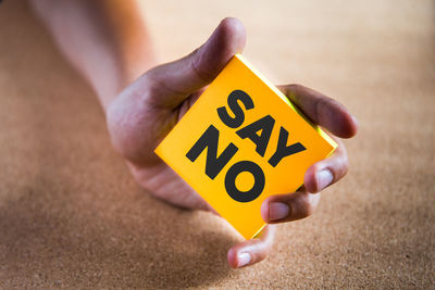 Cropped hand holding yellow sticky note with say no text