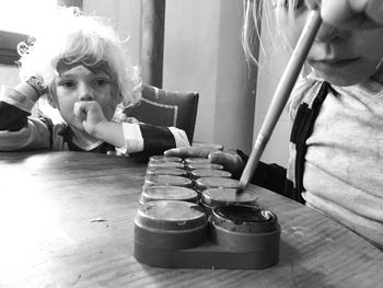 Portrait of boy sitting by sister dipping brush in palette