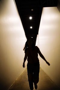 Full length of woman standing in illuminated tunnel