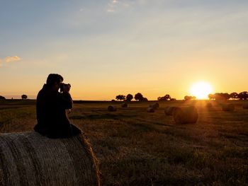 Scenic view of field against sky during sunset with photographer