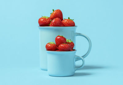 Close-up of strawberries and fruit on table against blue background