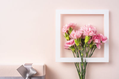 Close-up of pink flower vase on table against wall