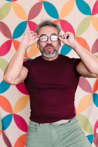 Portrait of man wearing hat standing against wall
