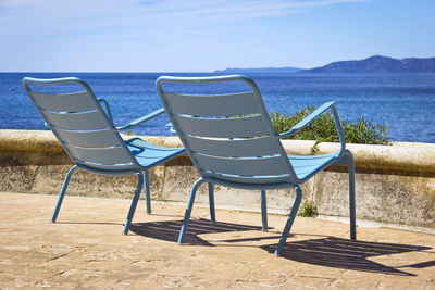 Chairs on beach against blue sky