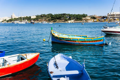 Sailboats moored on sea against clear blue sky