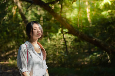 Thoughtful woman standing in forest