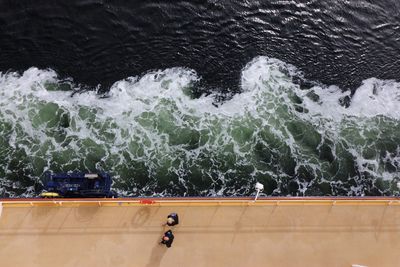 Directly above view of people walking on ferry deck in sea