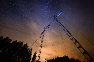 Low angle view of silhouette electricity pylon against sky at night