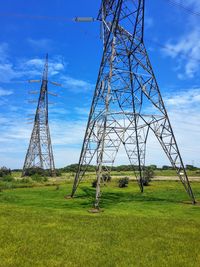 Low angle view of electricity pylon on field against sky