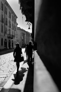 Rear view of people walking on street amidst buildings in city