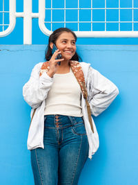 Young woman standing against blue background