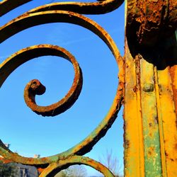 Low angle view of rusty gate detail against clear blue sky