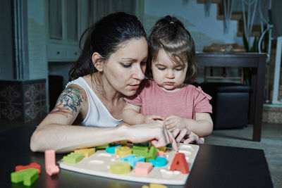 A mother teaching her daughter the letters of the alphabet. concept of learning