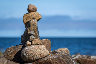 Cross on rock by sea against sky