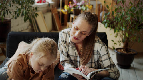 Mother and daughter reading book at home