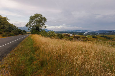 Road amidst field against sky