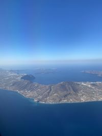 Aerial view of sea and mountain against blue sky