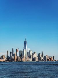 City at waterfront against blue sky