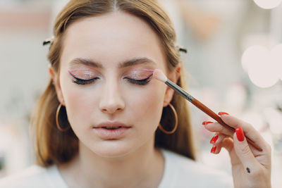 Close-up of young woman applying make-up artist