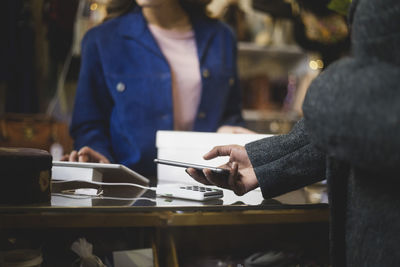 Midsection of customer doing contactless payment at clothing store