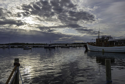 Sailboats moored in sea against sky during sunset