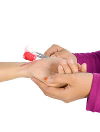 Close-up of hand holding red flowers against white background