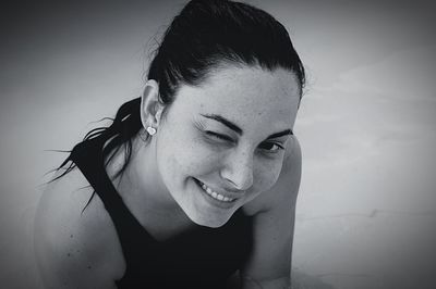 Close-up portrait of smiling woman winking outdoors