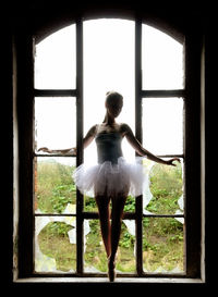 Full length of ballerina posing on broken window sill