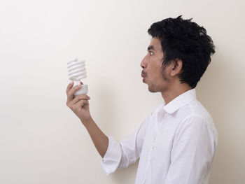 Side view of young man looking away against white background