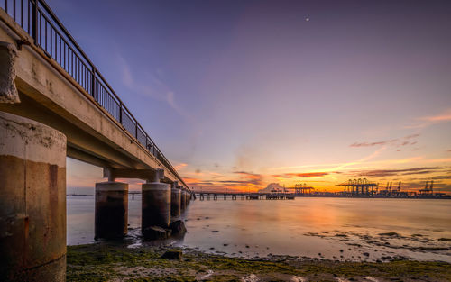 Pier over sea against sky at sunset