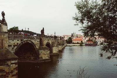 Bridge over river in city against sky